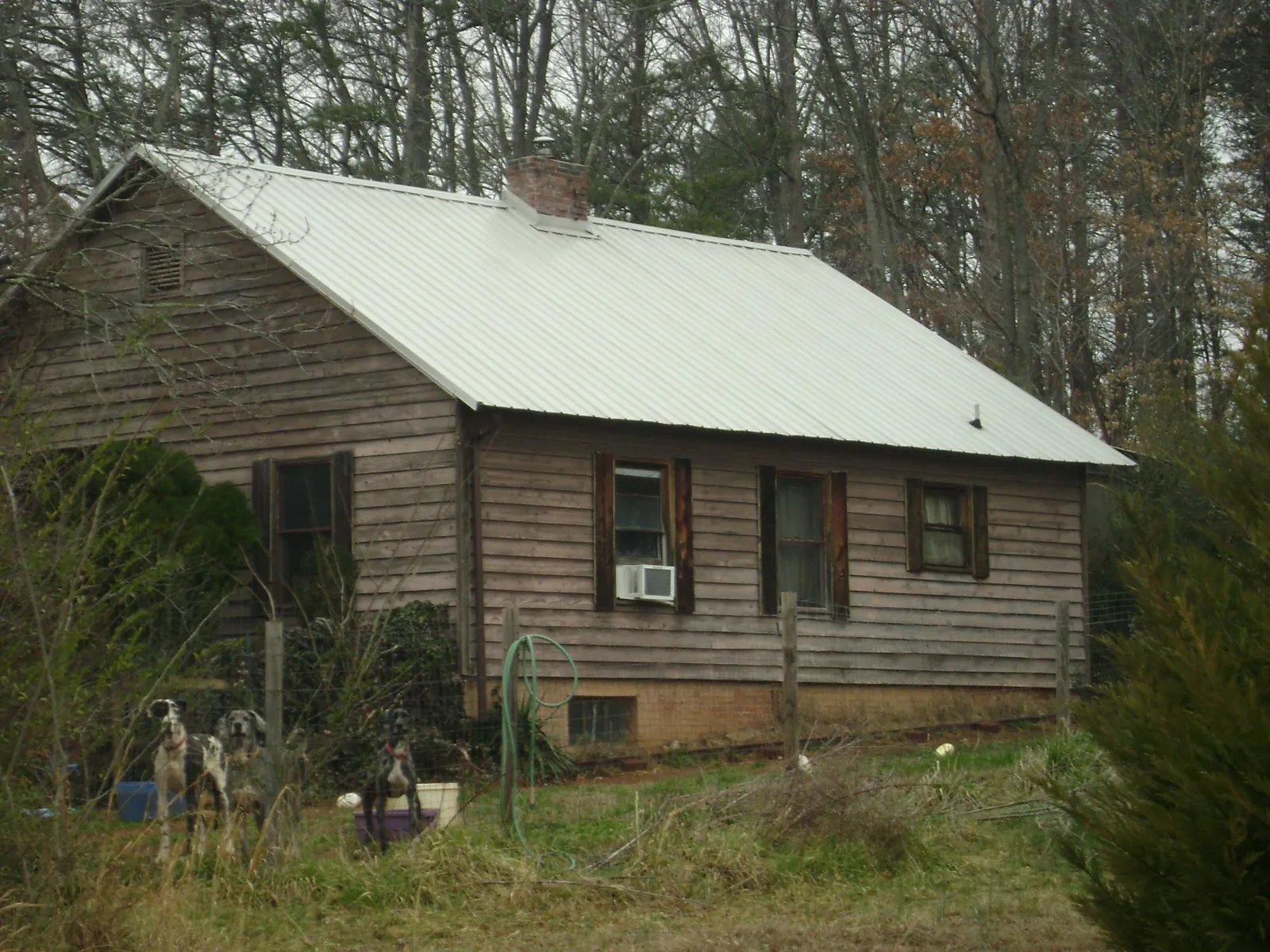 White metal roof on an old wood sided farmhouse, from a Metal Roof Installation job in Mount Pleasant