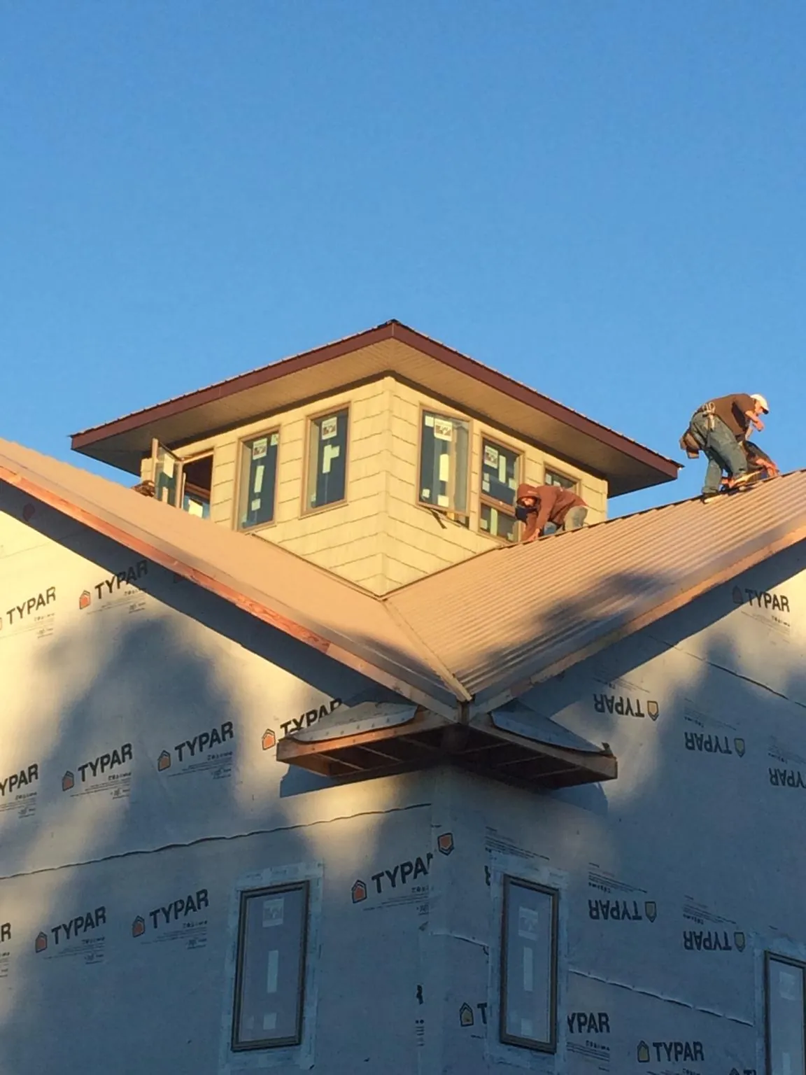 Roofers working around a rooftop cupola on a new metal roof at sunset — Roof Waterproofing in Mount Pleasant by Roofing Brothers